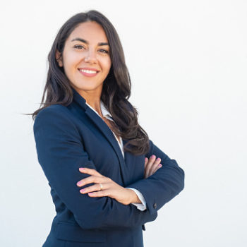 Smiling confident businesswoman posing with arms folded. Happy beautiful black haired young Latin woman in formal suit standing for camera over white studio background. Corporate portrait concept